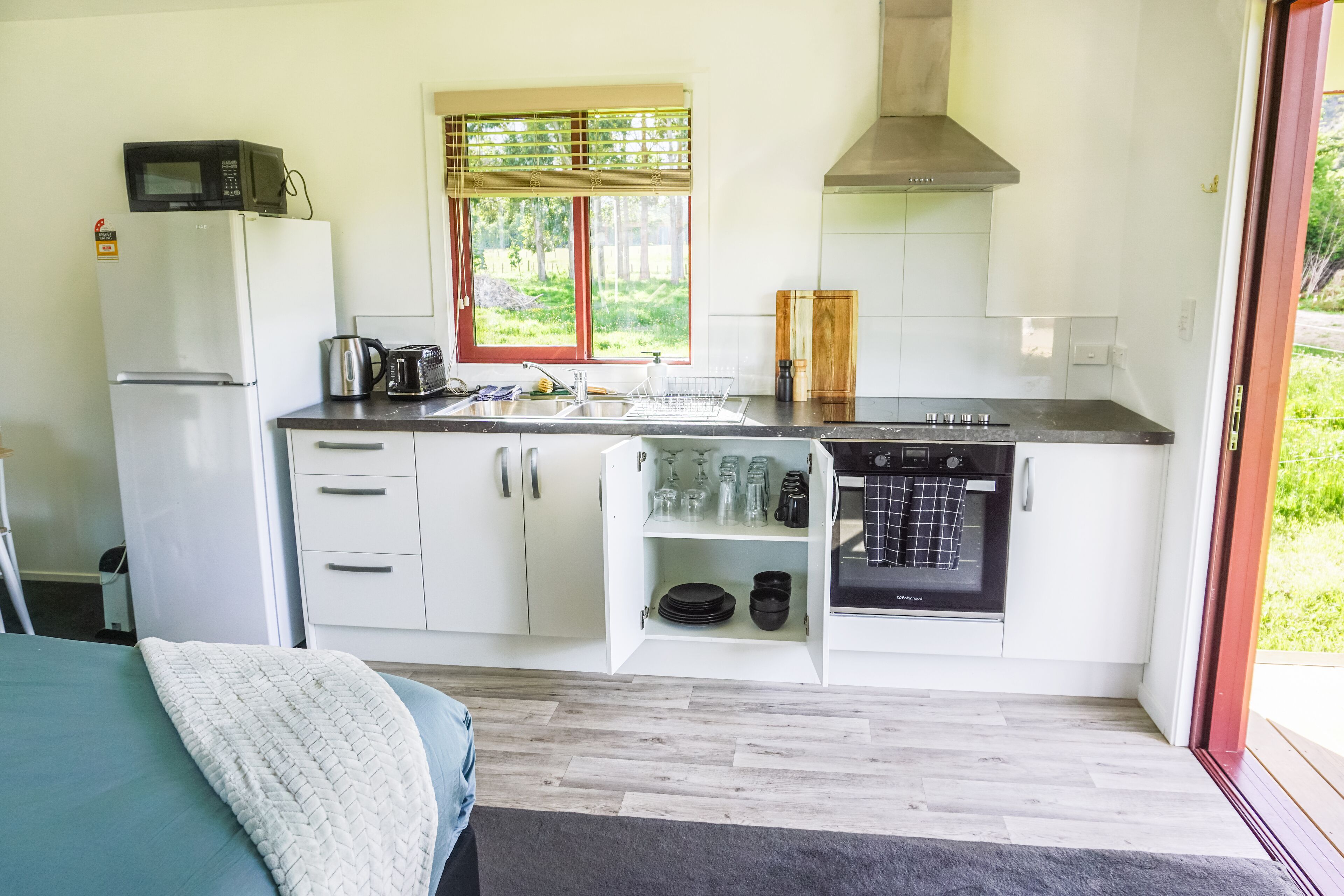 A compact kitchen with a refrigerator, microwave, sink, and oven.