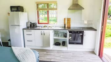 A compact kitchen with a refrigerator, microwave, sink, and oven.