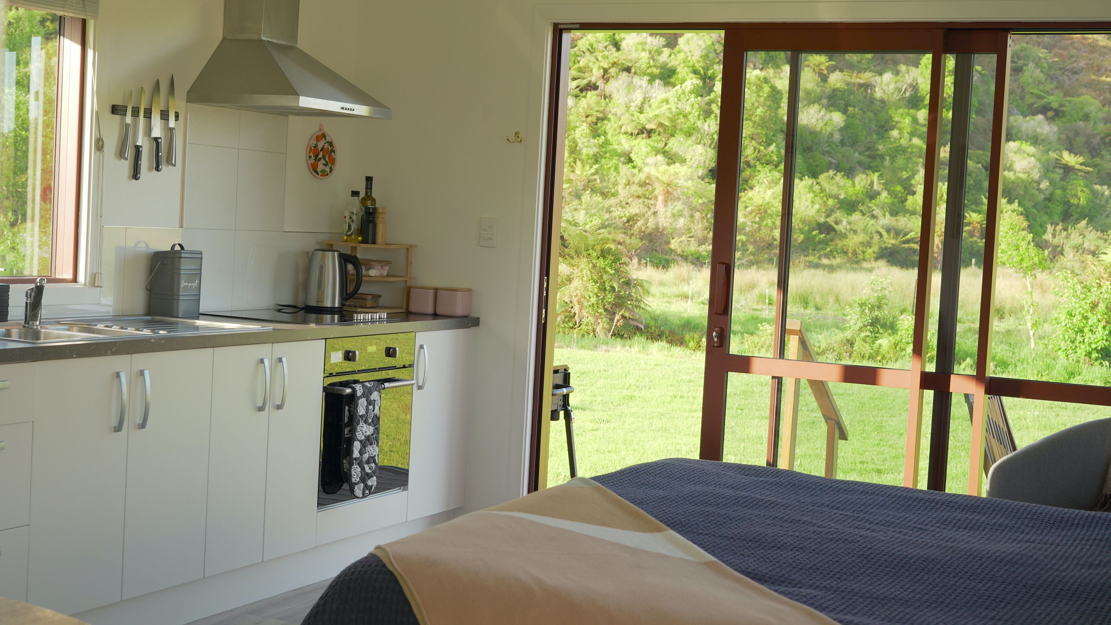 Un dormitorio con una ventana grande, una cama y vistas a un jardín.