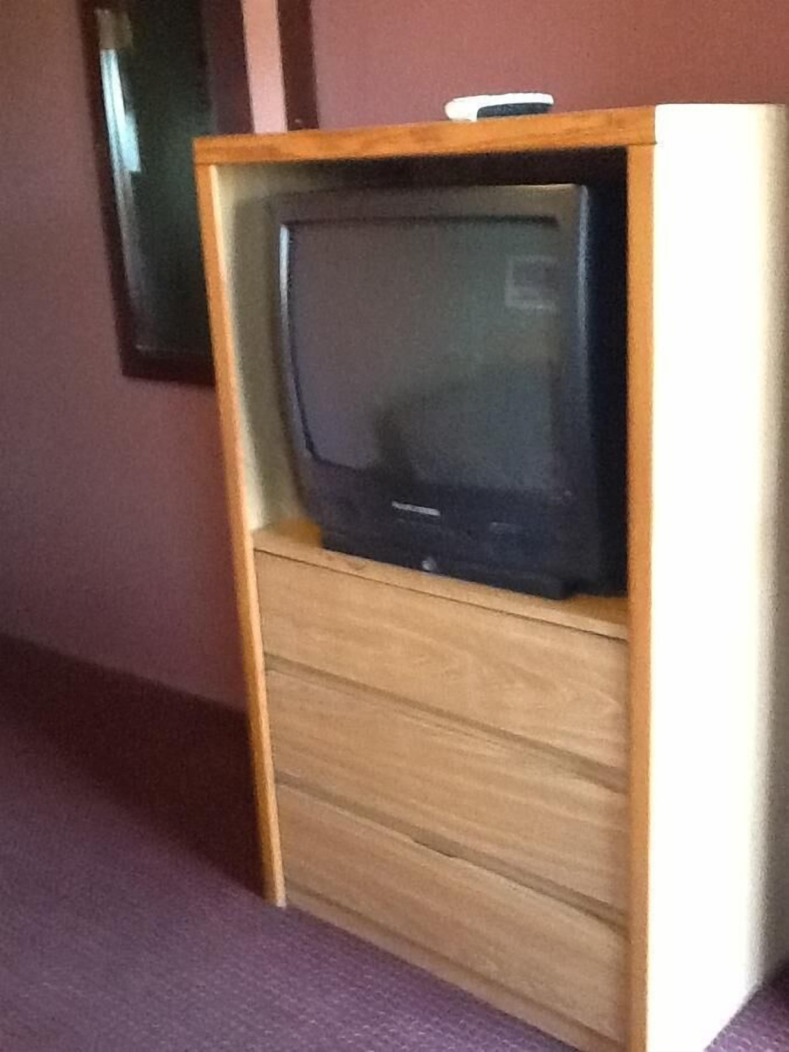 A television set in a wooden cabinet with a drawer below it.
