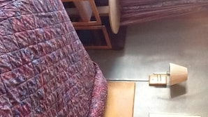 A room with a wooden bed frame, a quilted bedspread, a wooden nightstand, and a small table with a lamp.