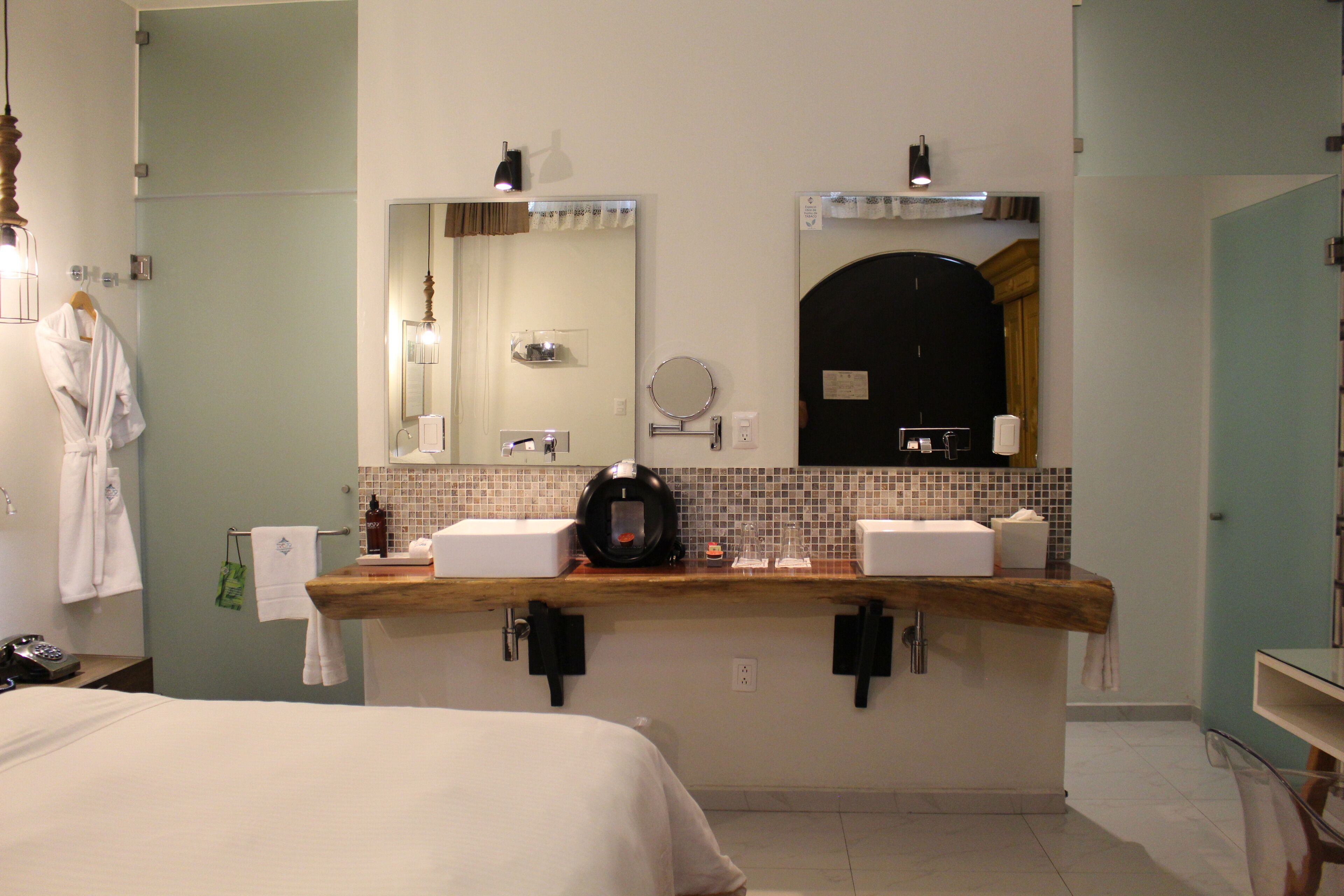 A hotel bathroom with a wooden vanity, two sinks, a large mirror, and a towel rack.