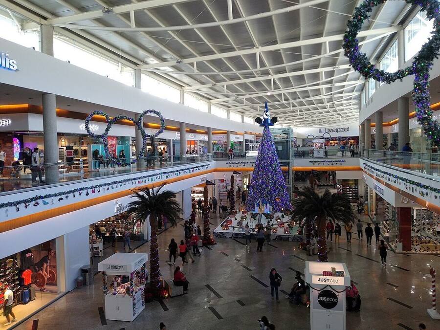 Ein mehrstöckiges Einkaufszentrum mit einem großen Weihnachtsbaum und festlicher Dekoration.