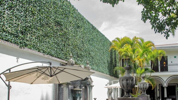 An outdoor patio area with tables and chairs, a fountain, and a decorative wall.