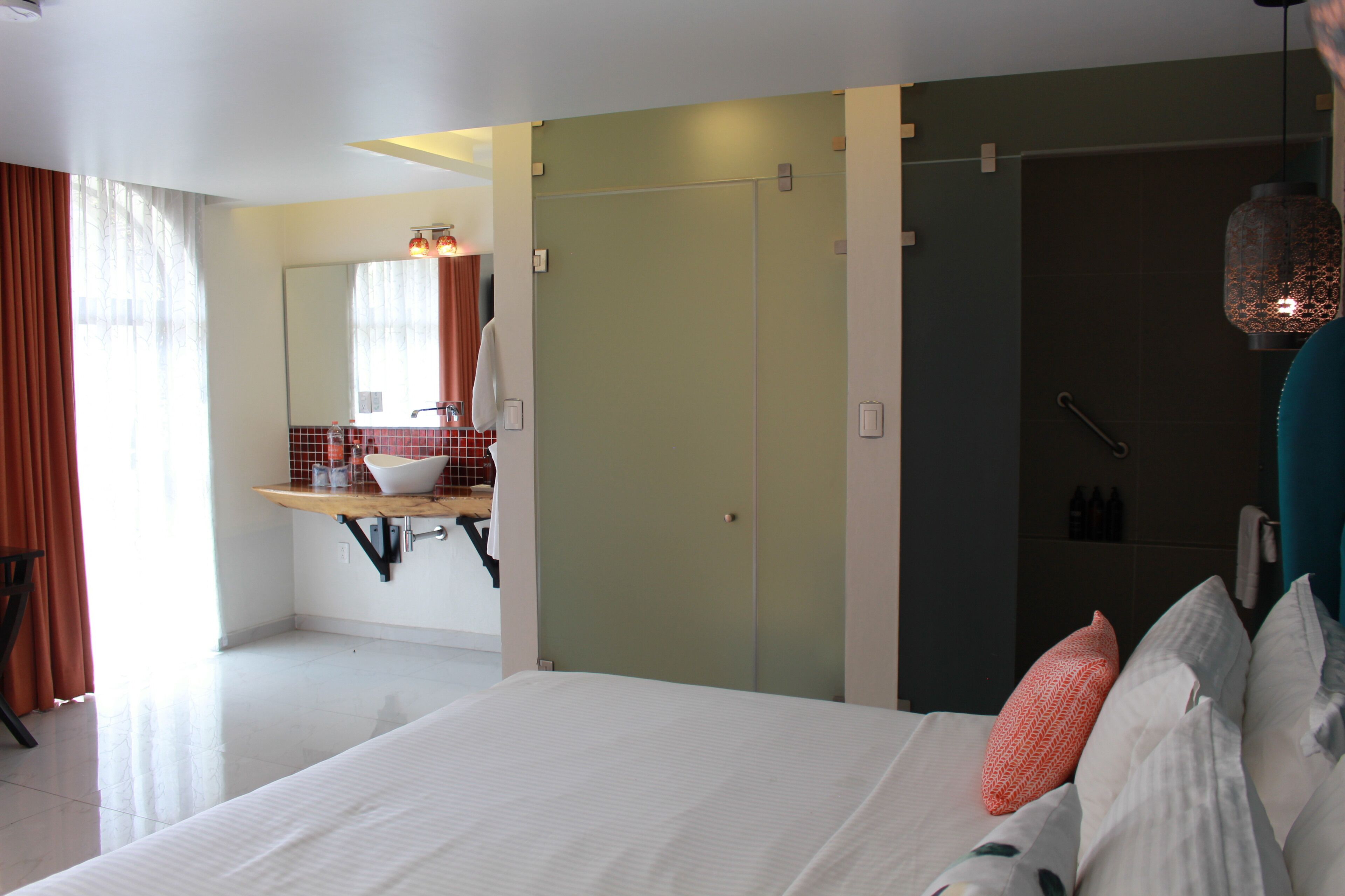 Ein modernes Hotelzimmer mit einem großen Bett, einem Schminktisch mit Spiegel und einer Duschkabine.