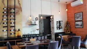 A restaurant with a long wine rack, hanging lights, and a patterned floor.