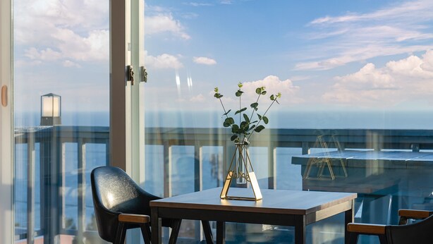 A balcony with a table, chairs, and a vase with plants. - Bluegrad Pension (Namhae)