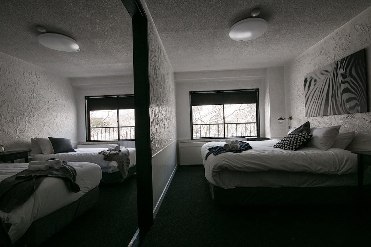 Una habitación de hotel con dos camas, un ventanal grande y una obra de arte con estampado de cebra en la pared.