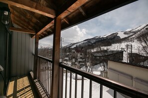 Un balcón de madera con vistas a montañas nevadas y una zona residencial.