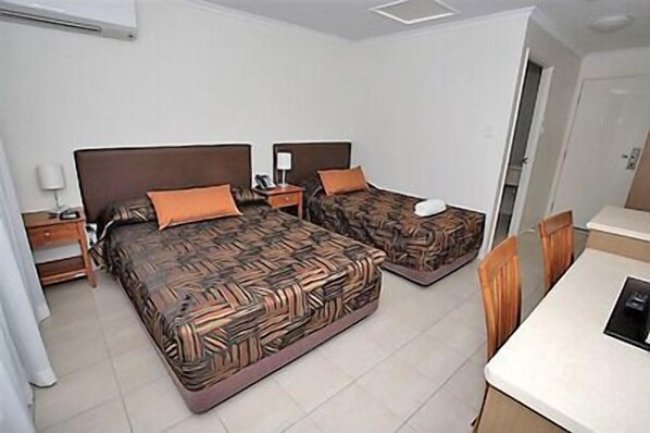 A hotel room with two beds, a desk, and a chair.