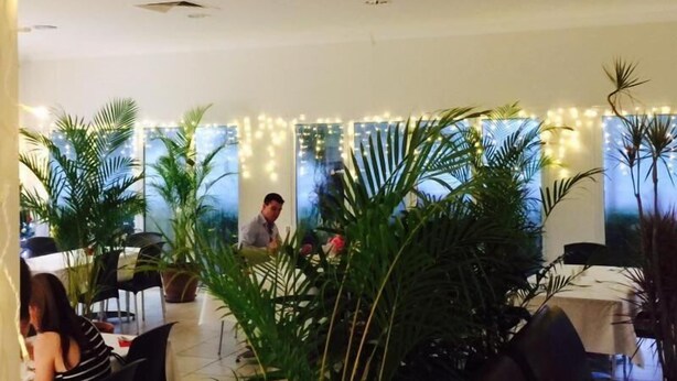 A restaurant with indoor plants, tables, and chairs. - Swag Motel (Middlemount)