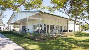 A modern building with a covered outdoor area, a paved walkway, and well-maintained grass. - Swag Motel (Middlemount)