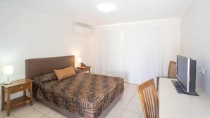 A hotel room with a single bed, a desk with a computer, and a chair. - Swag Motel (Middlemount)