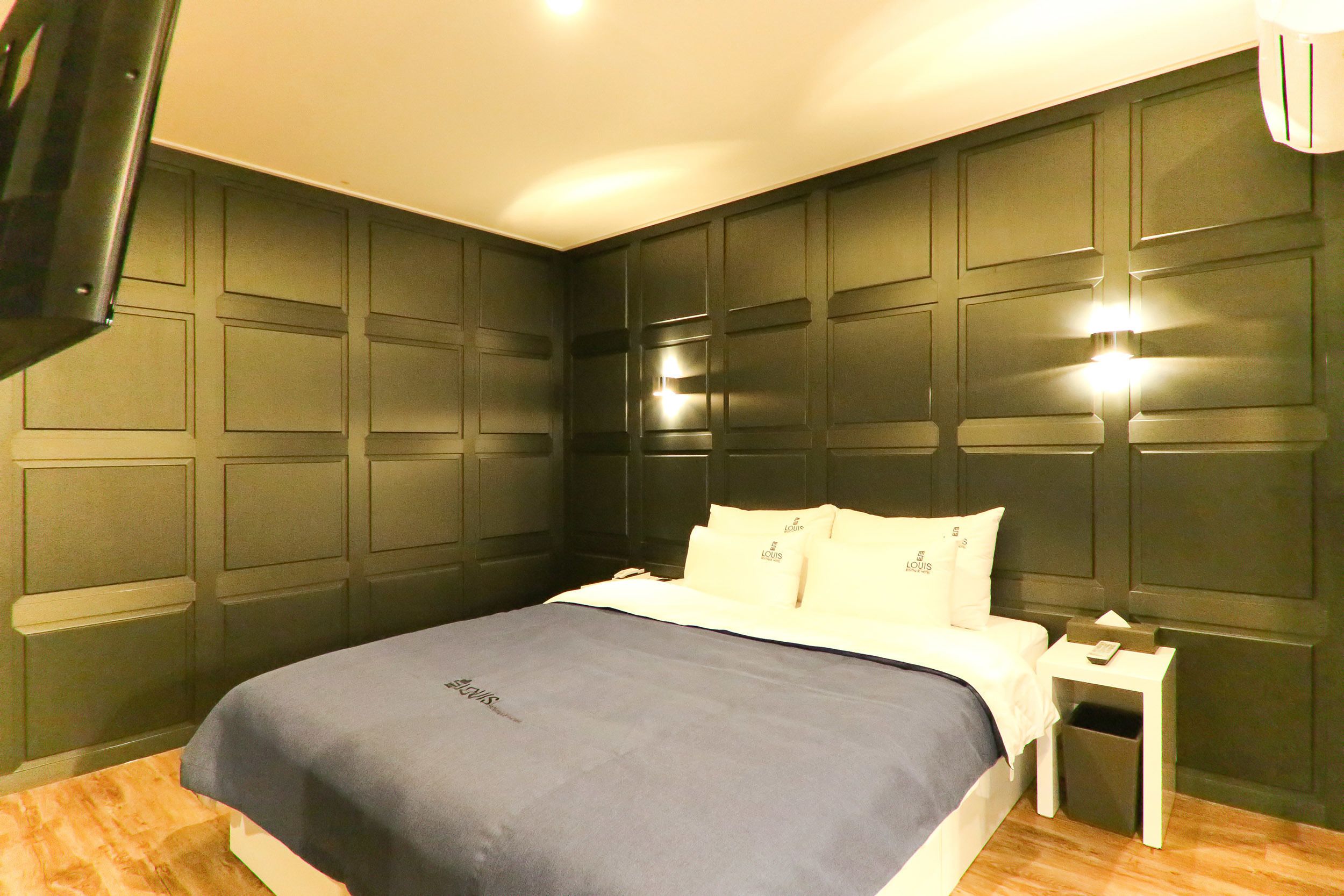 A hotel room with a bed, a nightstand, and a wall-mounted TV.