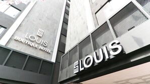 Un bâtiment sur lequel on peut voir en évidence l’enseigne « LOUIS BOUTIQUE HOTEL ».