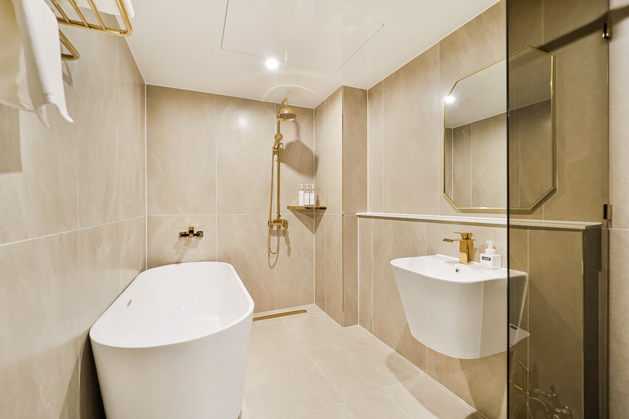 Un baño moderno con una bañera independiente, un lavamanos empotrado y un espejo grande.