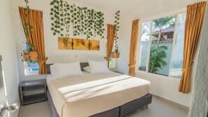 A bedroom with a large bed, a nightstand, a window with curtains, and hanging plants. - Hotel PaloVerde Villas Campestres (Villavicencio)