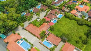 An aerial view of a residential area with multiple houses, each featuring a swimming pool and surrounded by greenery. - Hotel PaloVerde Villas Campestres (Villavicencio)
