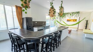 A modern kitchen with a large island, black bar stools, and hanging plants. - Hotel PaloVerde Villas Campestres (Villavicencio)