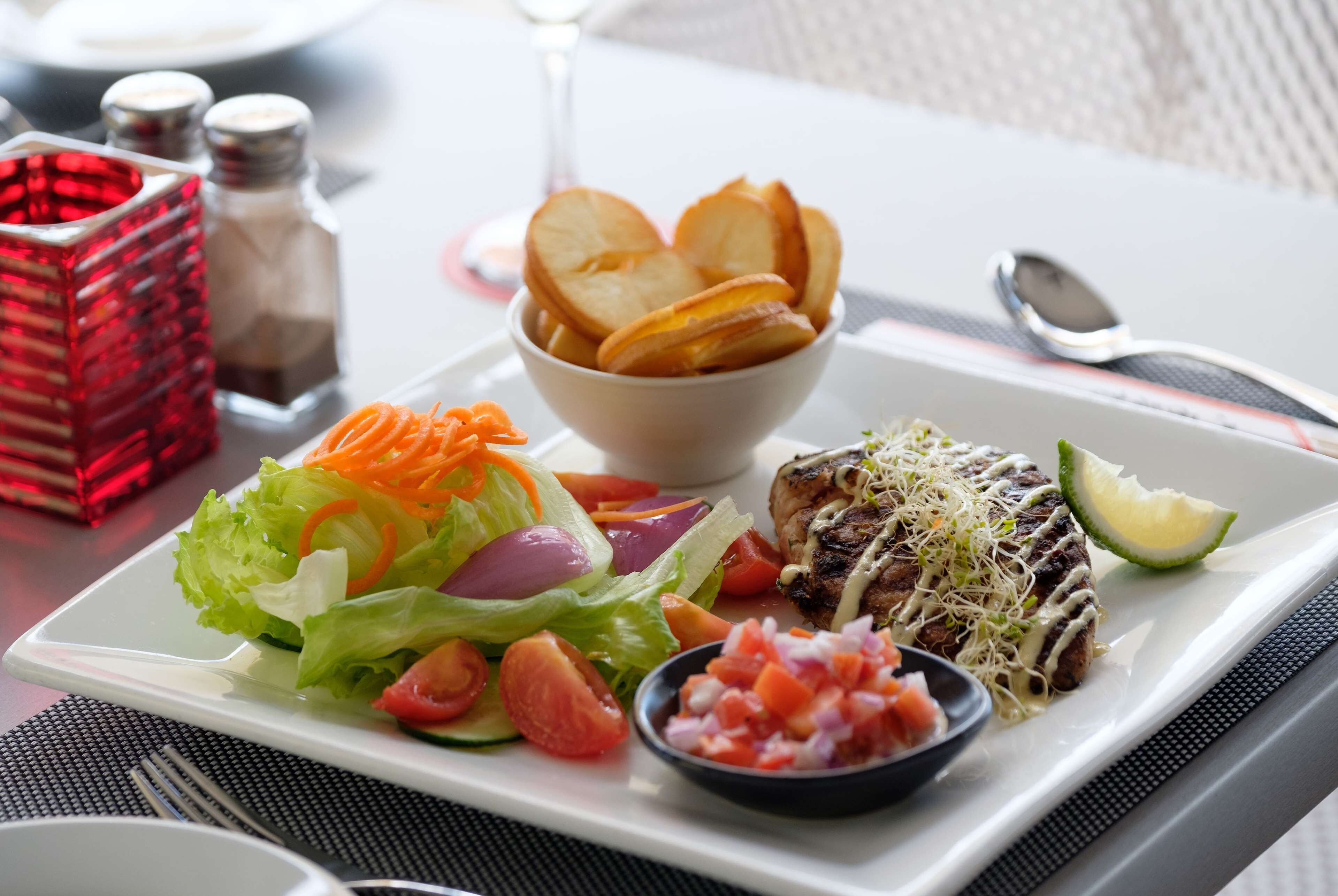 Un plato con carne a la parrilla, ensalada y papas fritas.