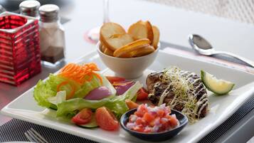 Un plato con carne a la parrilla, ensalada y papas fritas.