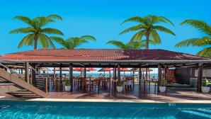 Ein Poolbereich mit überdachter Sitzgelegenheit, Palmen und Blick auf das Meer.