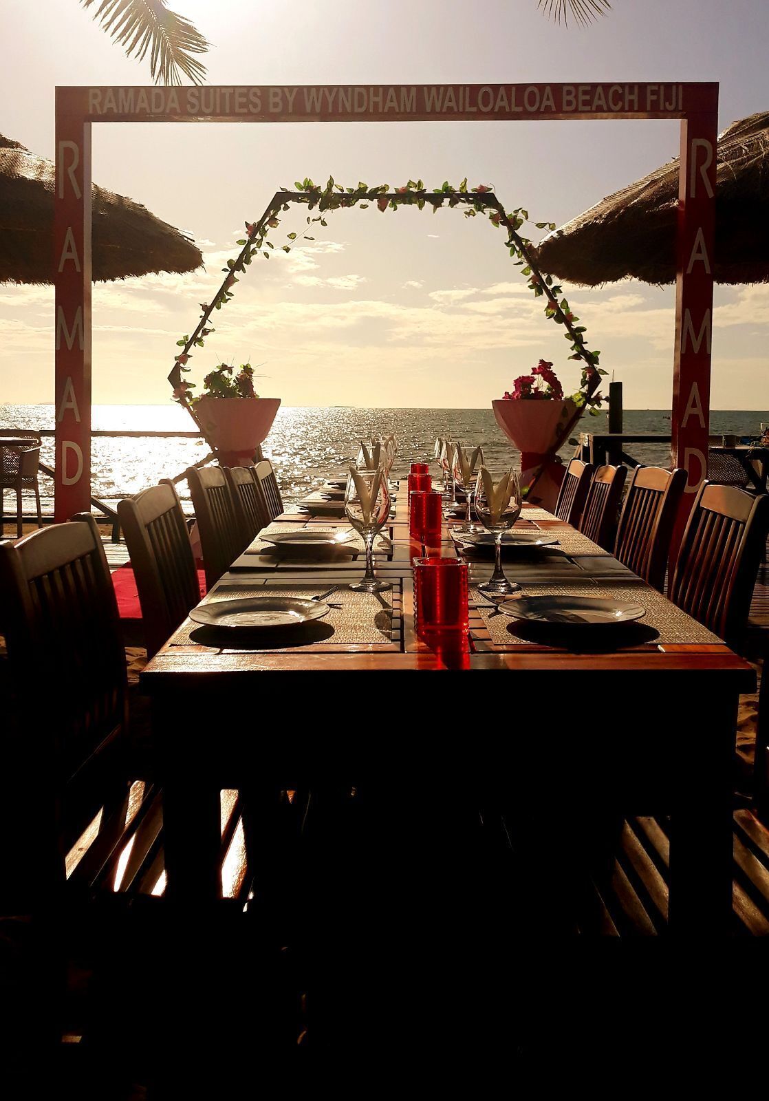 Mesa para dos servida en Ramada Suites by Wyndham Waiola Beach Fiji, con vista al océano.