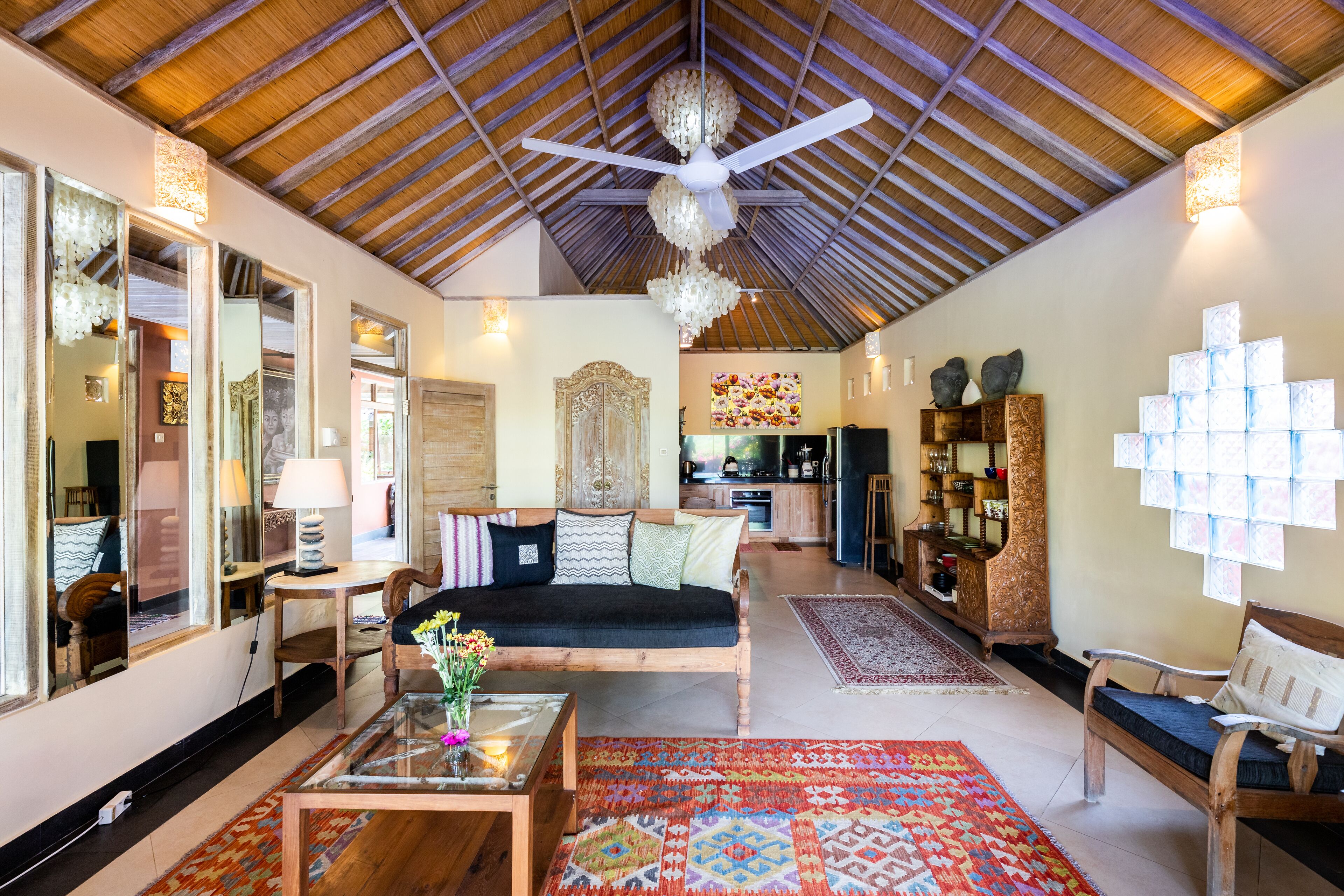 A spacious living area with a high ceiling, a ceiling fan, a sofa, a coffee table, and a patterned rug.
