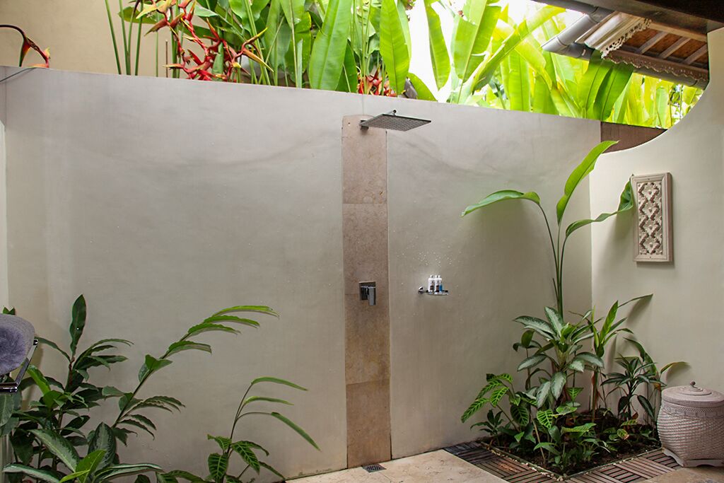 A spa area with a tiled floor, a water feature, and lush green plants.