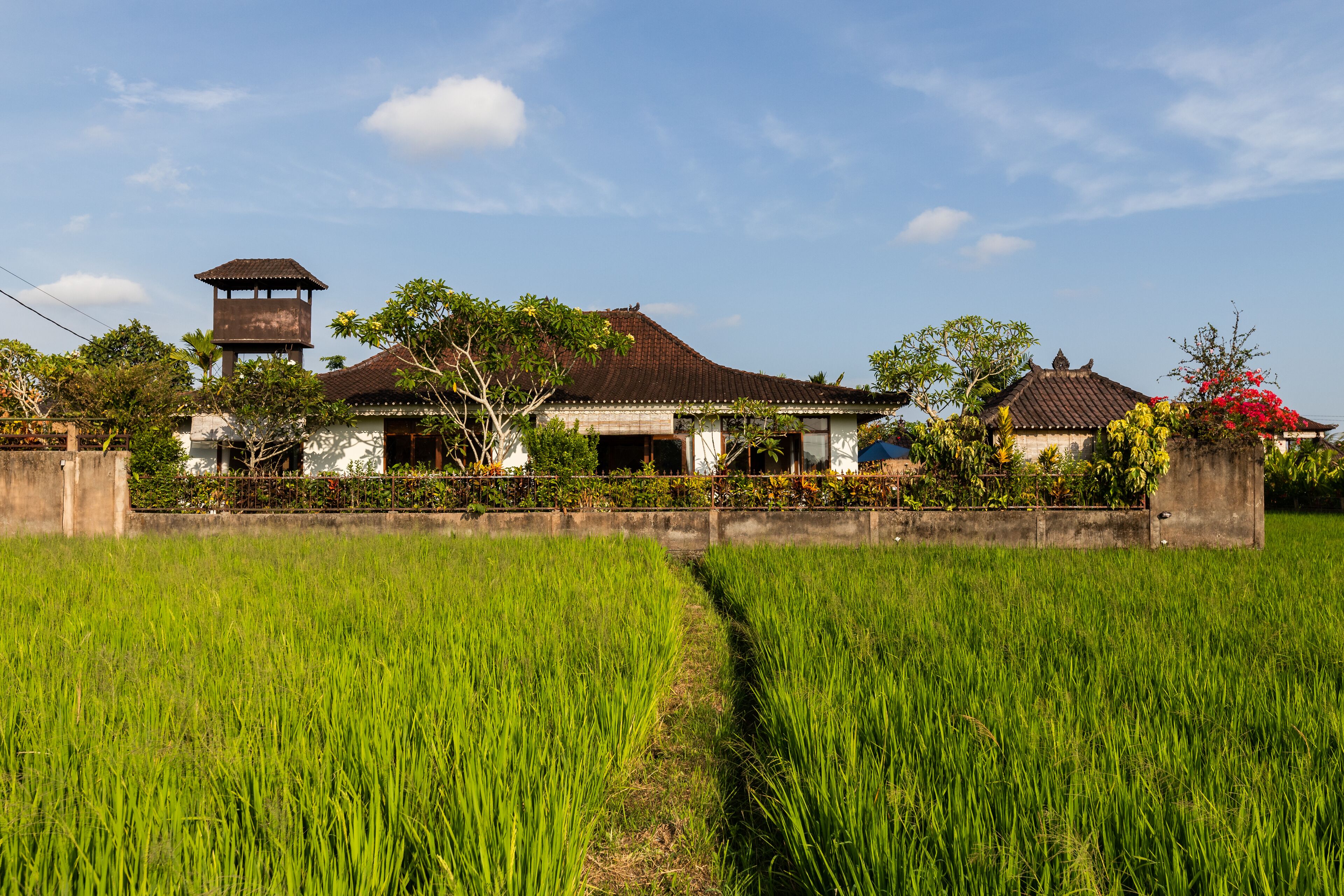 A traditional house with a tower, surrounded by lush green fields.