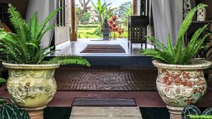 A pathway leading to a stage with a backdrop of greenery and a seated figure. - Devi's Place (Ubud)