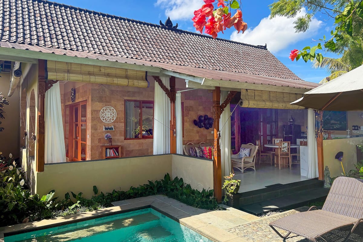 Uma casa com telhado de cerâmica, piscina e área de varanda coberta.