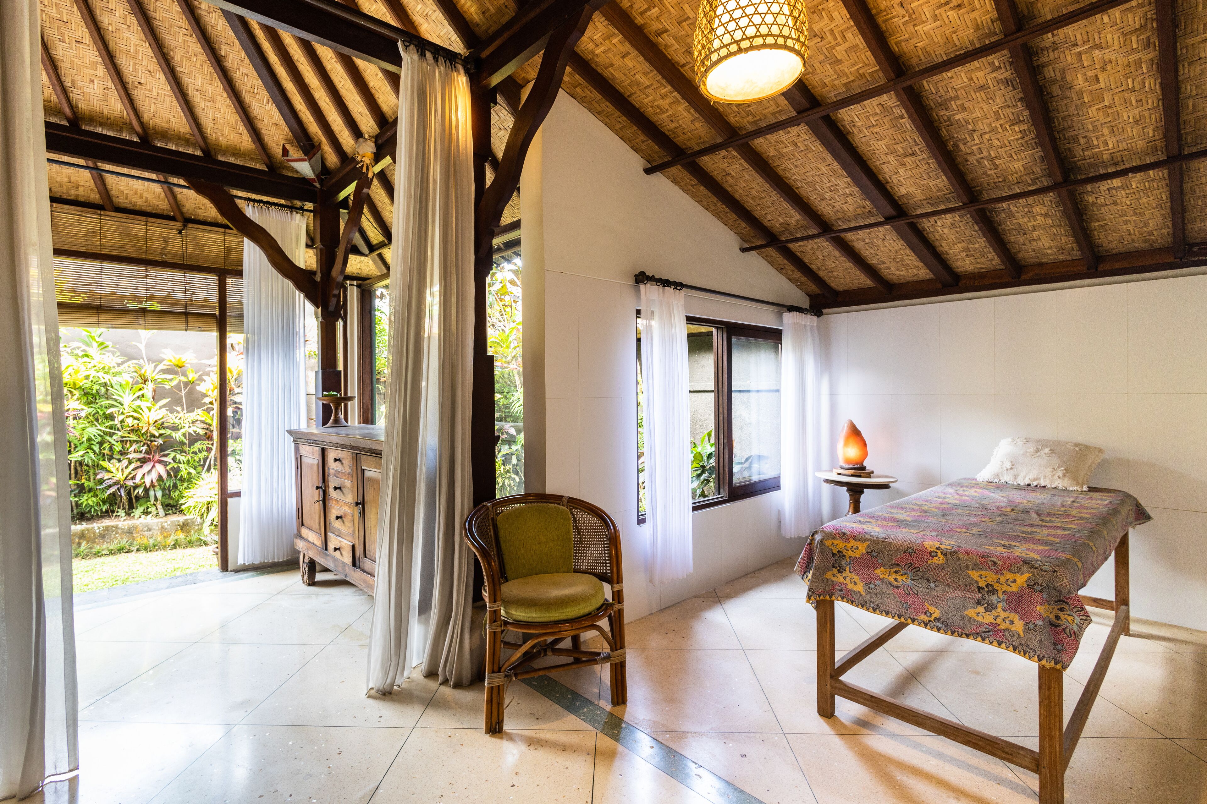 A room with a bed, a chair, a table, and a window.