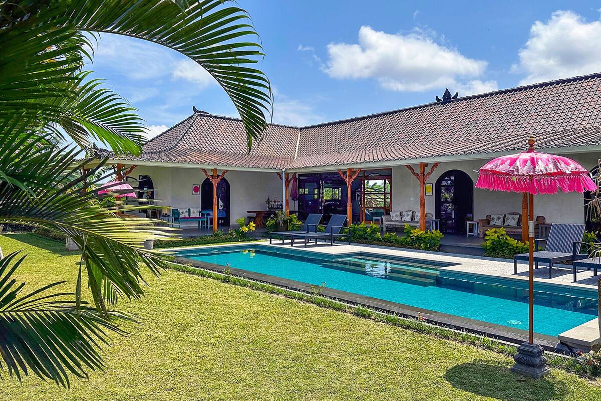 Uma área à beira da piscina com cobertura em azulejos, mobiliário de exterior e piscina.