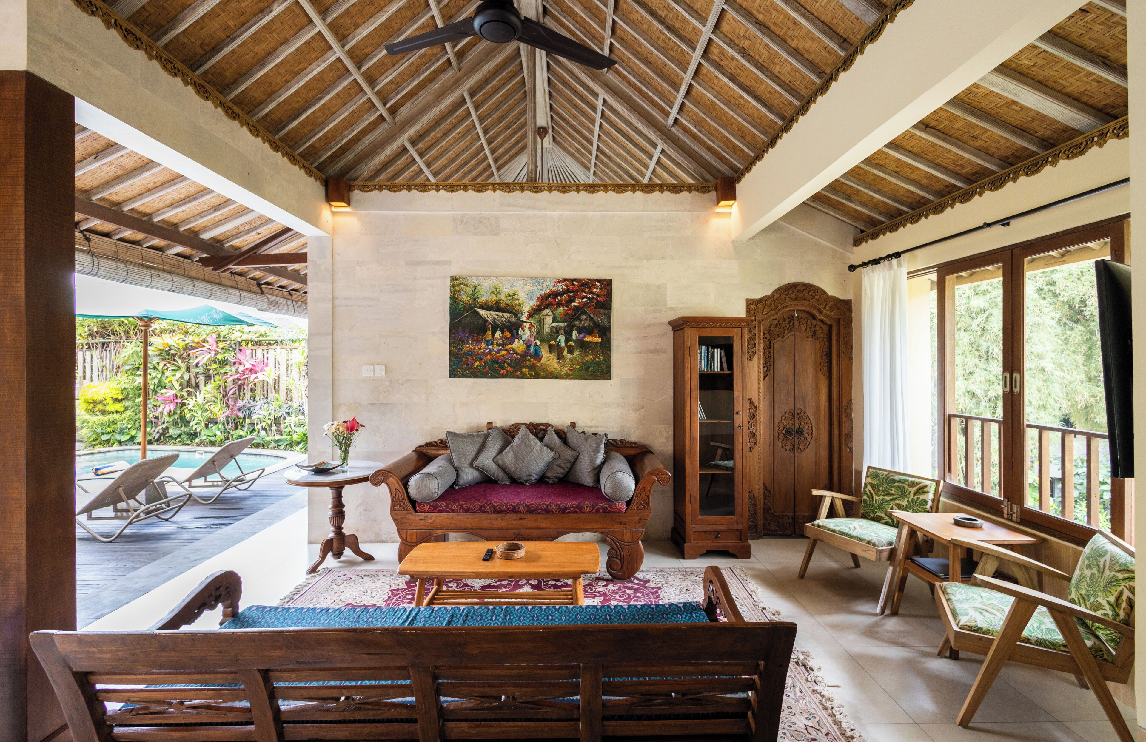 A cozy lounge area with a wooden bench, cushioned seating, and a ceiling fan.