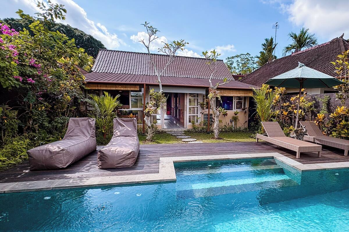Uma área de piscina com espreguiçadeiras e uma casa com telhado telhado.