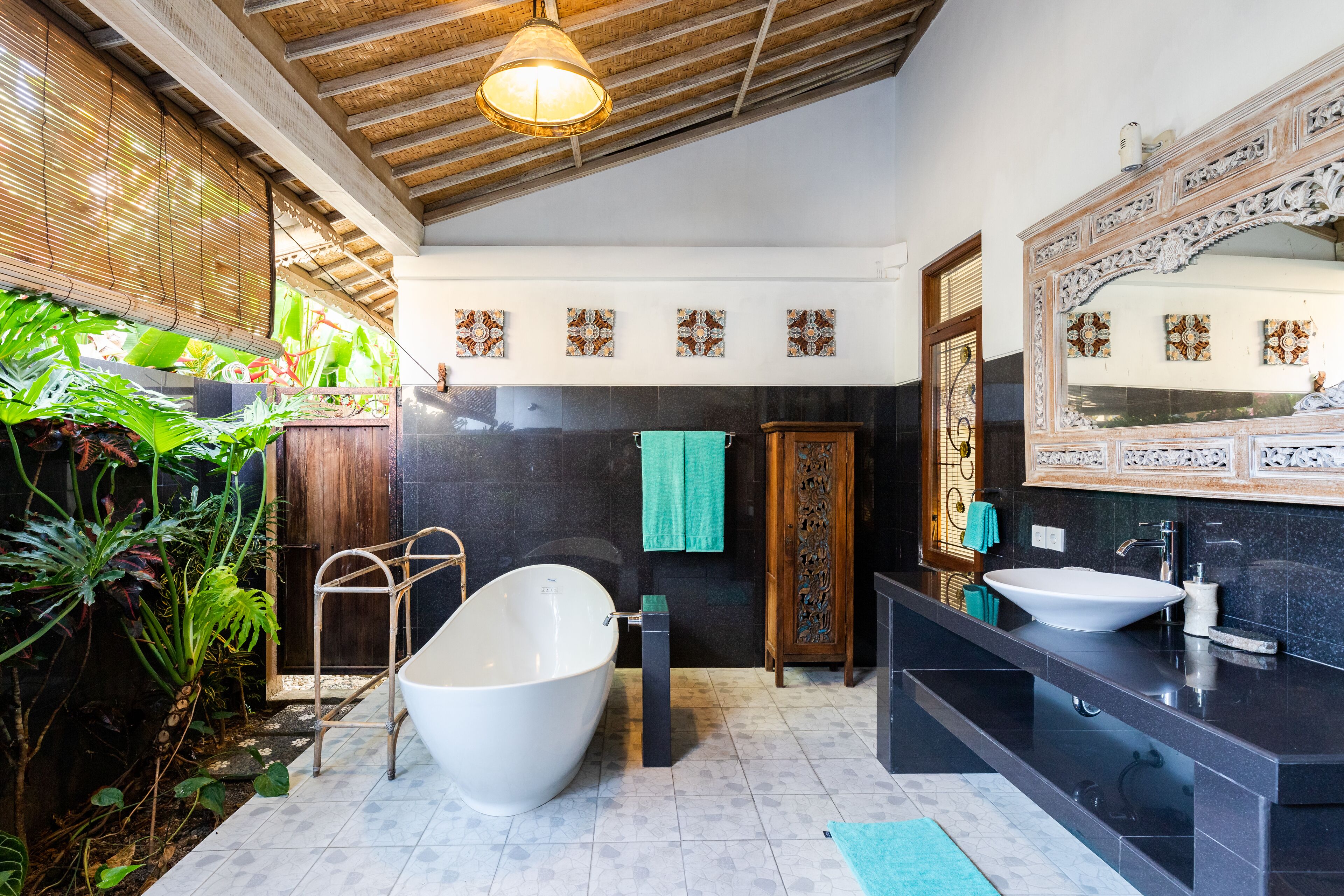 A modern bathroom with a freestanding bathtub, a large mirror, and a black countertop with a sink.
