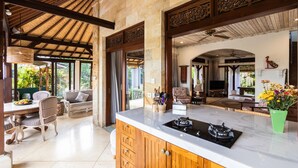 A spacious kitchen with a marble countertop, wooden cabinets, and a gas stove. - Devi's Place (Ubud)