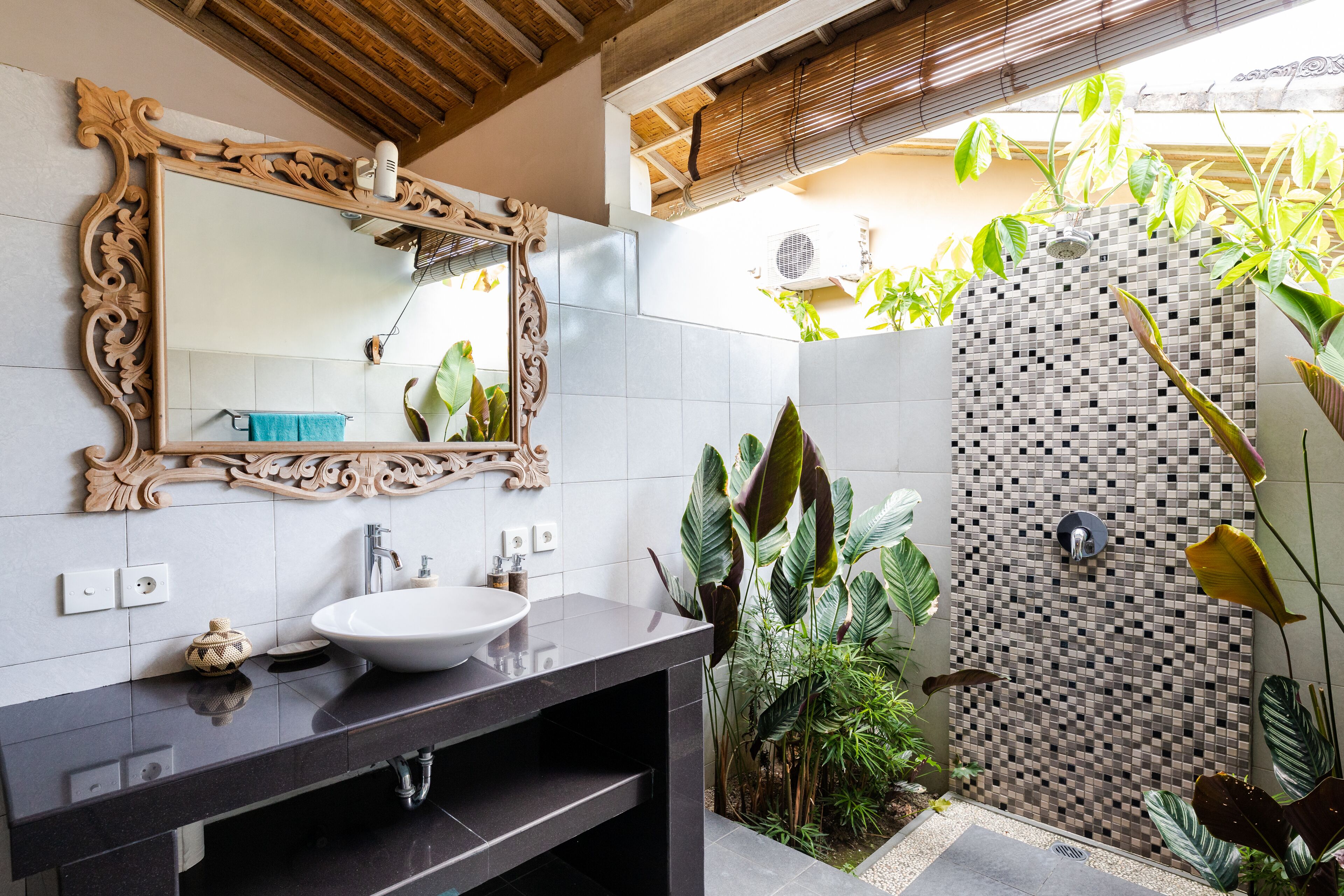 Ein Badezimmer mit einem großen Spiegel, einem Waschbecken und einer Duschkabine mit Mosaikwand.