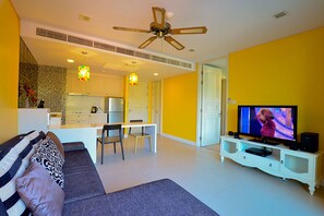 A living room with a sofa, TV, and a dining area with chairs and a table.