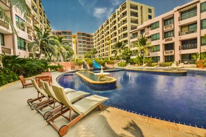 A hotel pool area with lounge chairs, a water fountain, and palm trees. - Marrakesh Residence Hua Hin by Puppap (Hua Hin)