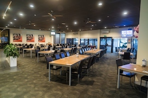 A conference room with multiple tables and chairs, ceiling fans, and large windows. - Sundowner Cabin and Tourist Park (Whyalla Norrie)