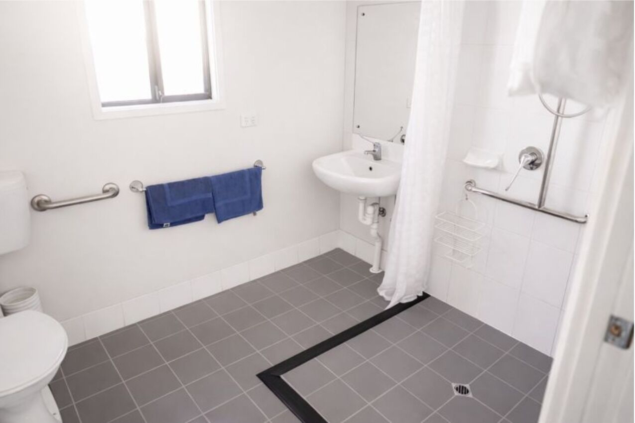A bathroom with a toilet, sink, and shower area.