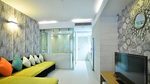 A modern hotel room with a yellow bed, a TV, and a mirror on the wall. - The Sanctuary Hua Hin by Puppap (Hua Hin)