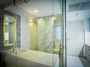 Ein modernes Badezimmer mit einer einbruchsicheren Duschkabine, einer großen weißen Badewanne und einer durch eine Glasabtrennung sichtbaren Toilette.