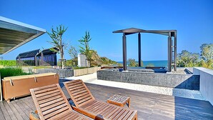 A wooden deck with lounge chairs and a small table, overlooking a pool and a clear blue sky. - The Sanctuary Hua Hin by Puppap (Hua Hin)
