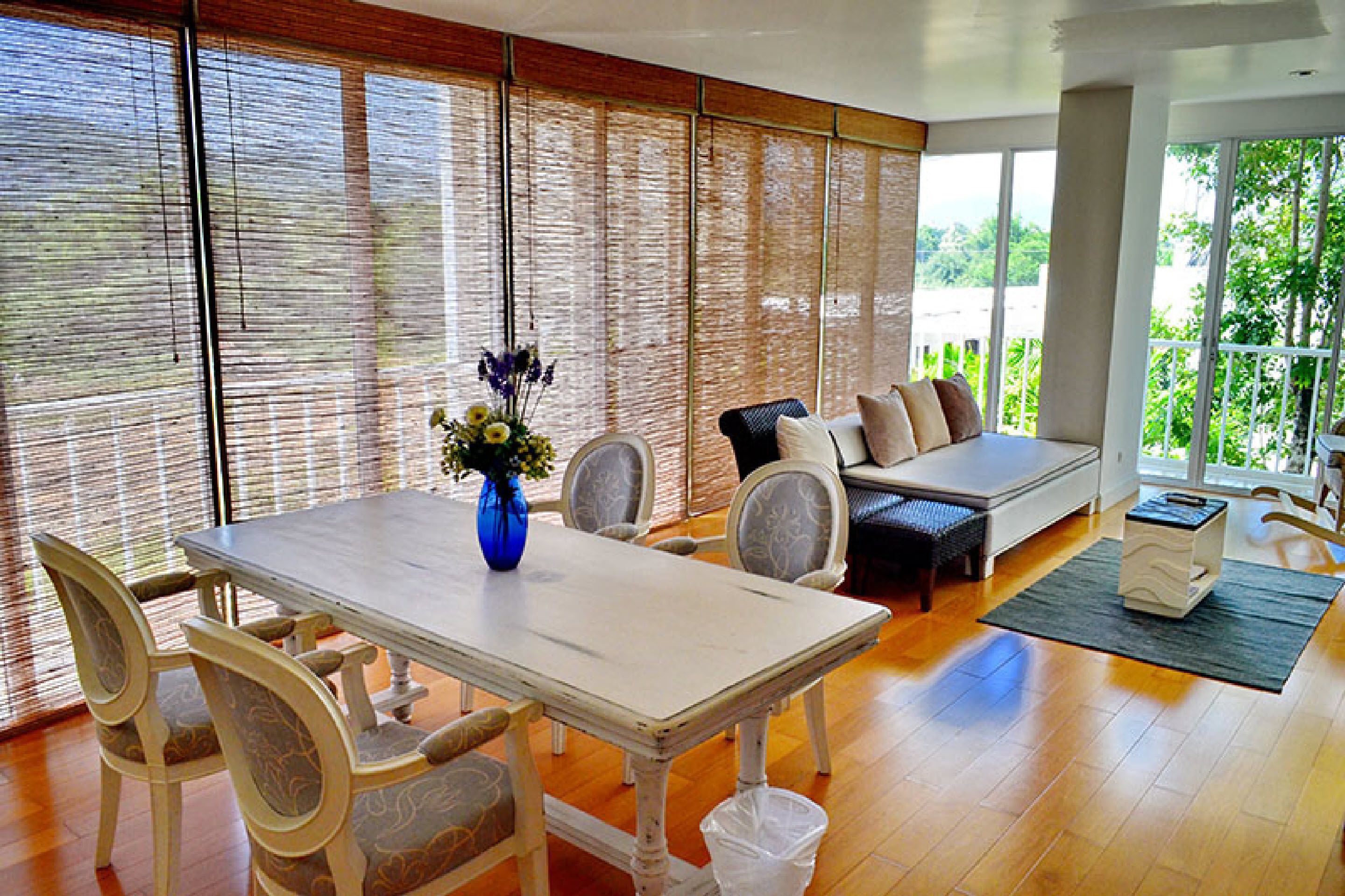 A dining area with a white table, chairs, and a vase of flowers.