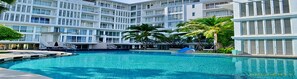 A modern hotel with a large swimming pool, palm trees, and a blue slide. - Malibu Hua Hin by Puppap (Hua Hin)