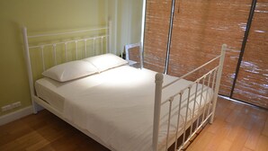 A single bed with white bedding in a room with wooden flooring and a window with a bamboo blind. - Malibu Hua Hin by Puppap (Hua Hin)