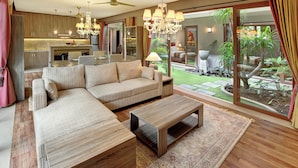 A modern living room with a sectional sofa, a coffee table, and a dining area with a chandelier. - Puri Sabina Bed & Breakfast (Jimbaran)
